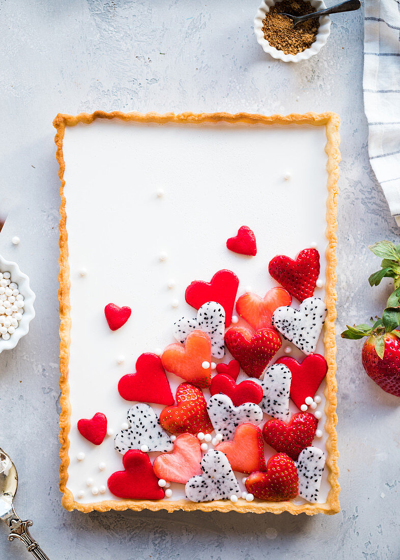 Rechteckige Vanille-Tarte mit herzförmigen Früchten dekoriert