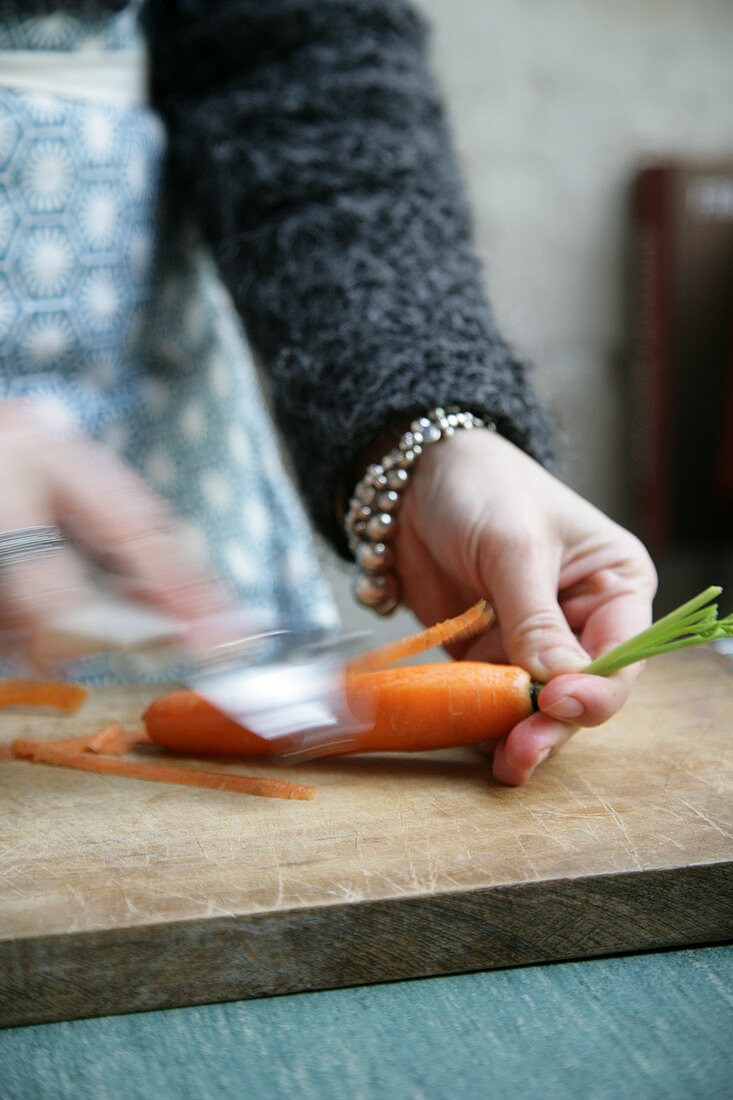 Frau schält Karotte mit Sparschäler