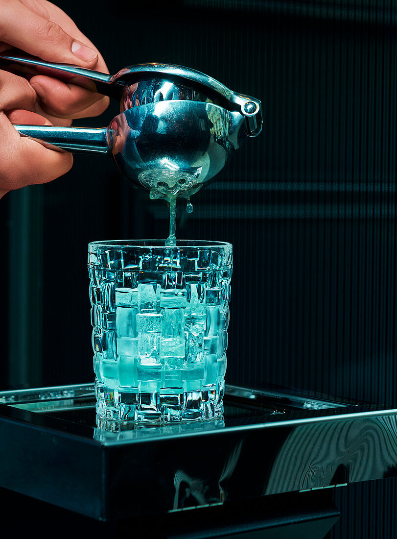 Bartender preparing a cocktail with a wine press