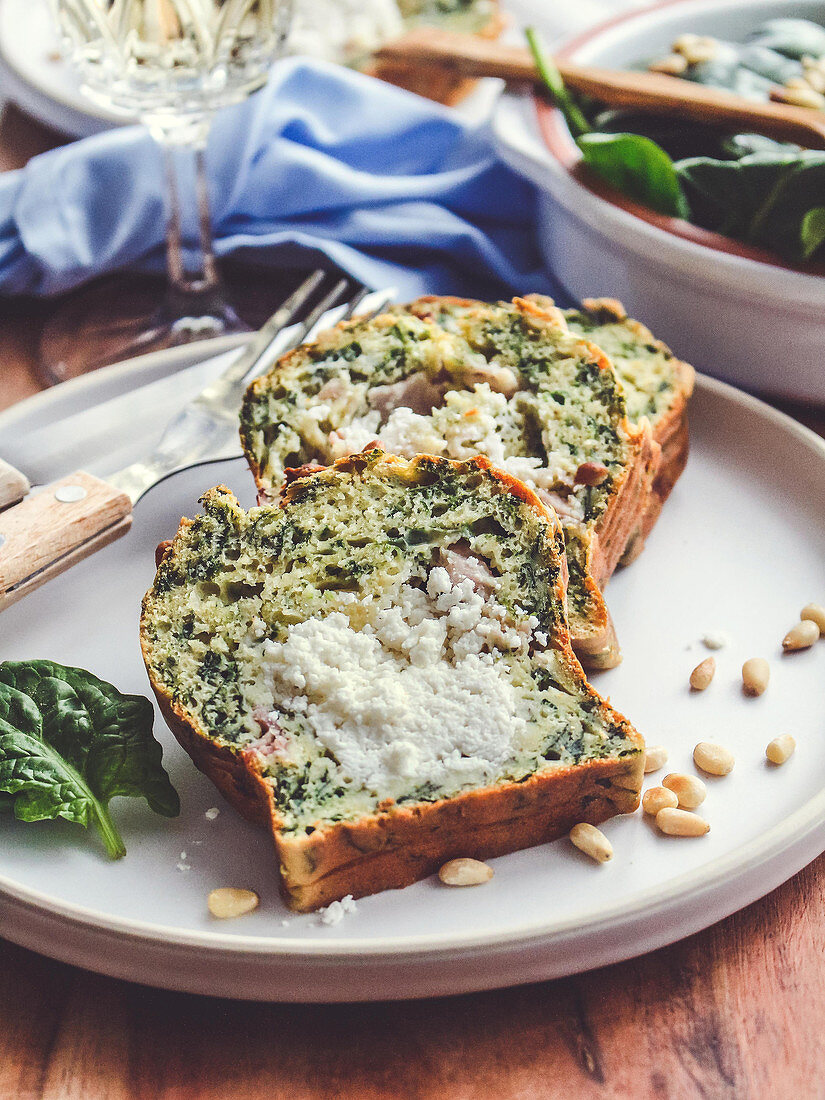 Spinach cake in a loaf tin with goat's cheese and pine nuts