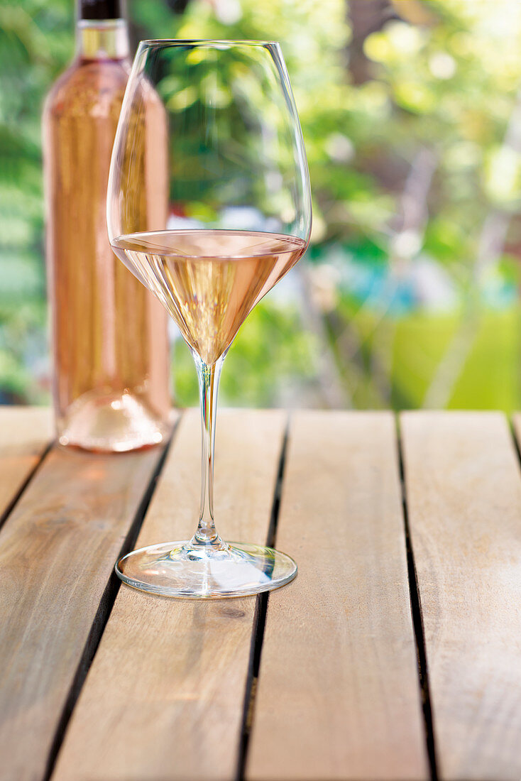 Flasche und Glas Rosewein auf Gartentisch