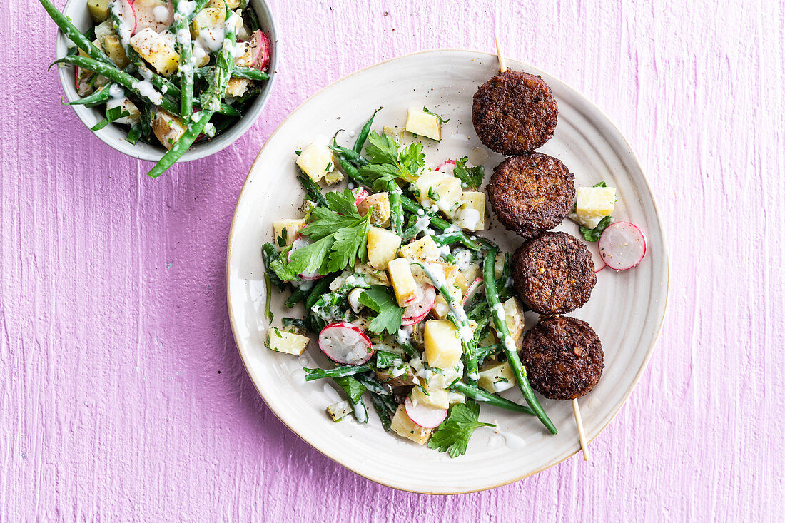 Vegetarian meatball skewer with potato and bean salad