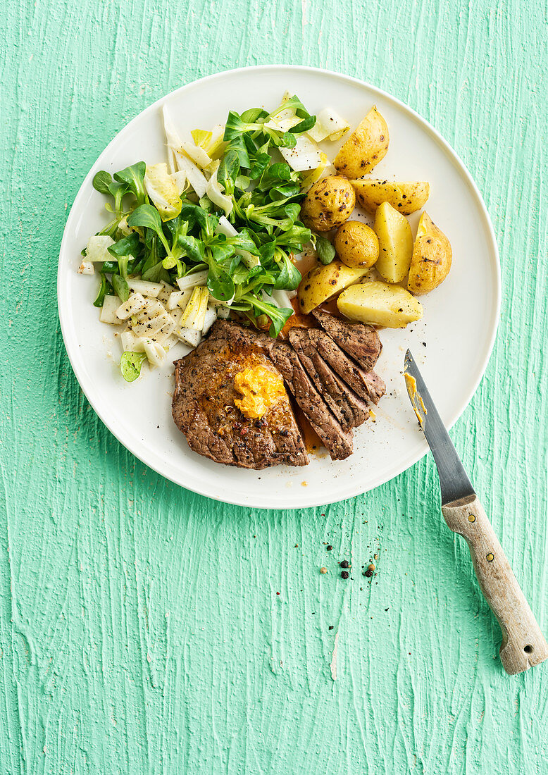 Beef steak with Beurre Maitre d'Hotel served with sautéed baby potatoes and field salad