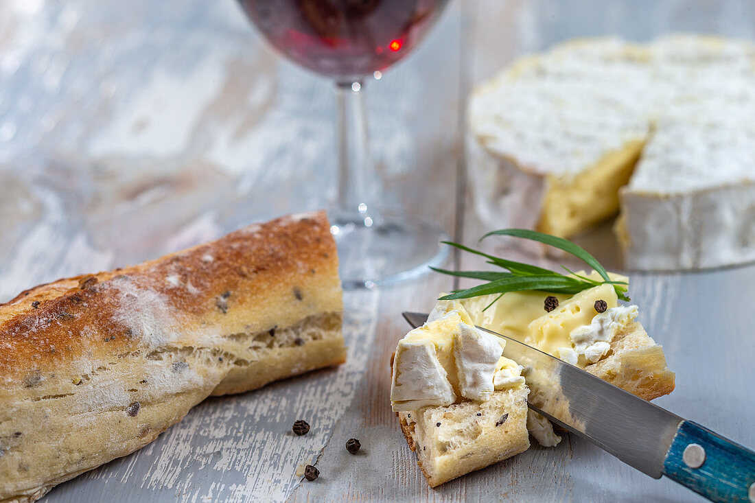 Camembert serviert mit Brot und einem Glas Rotwein