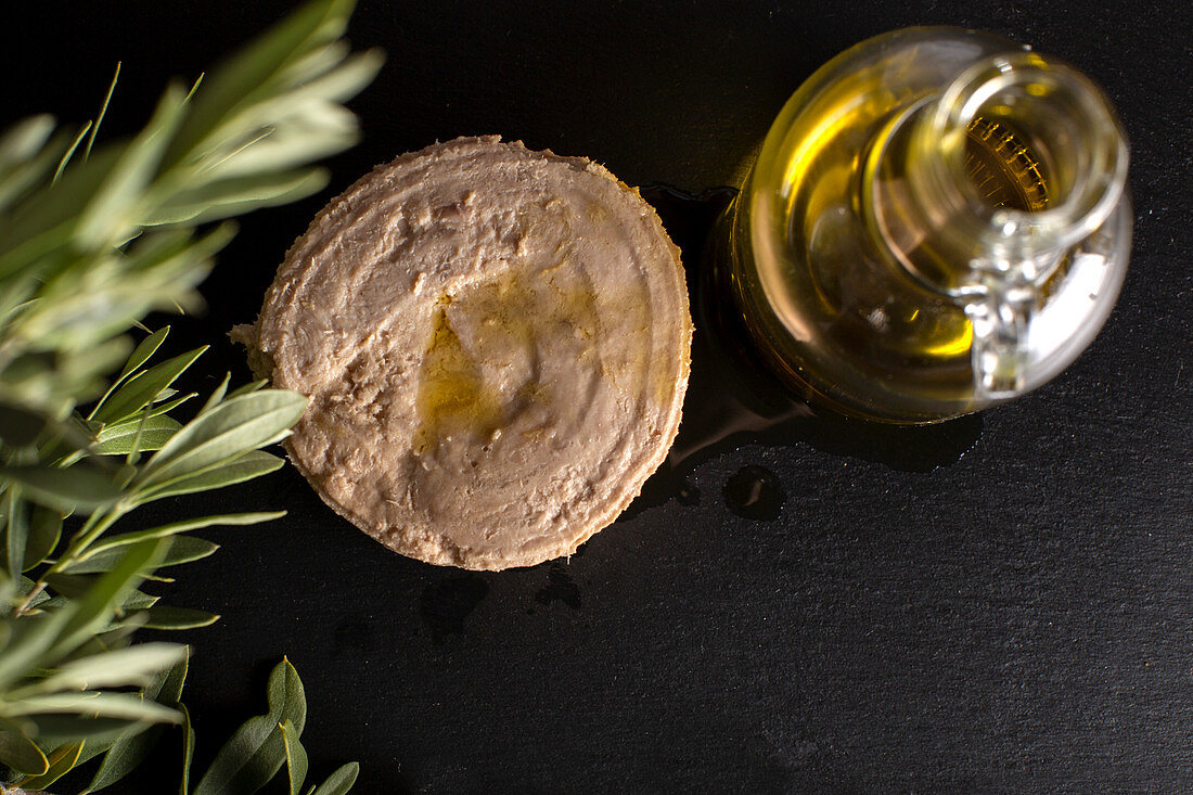 Tuna in a tin next to a bottle of olive oil