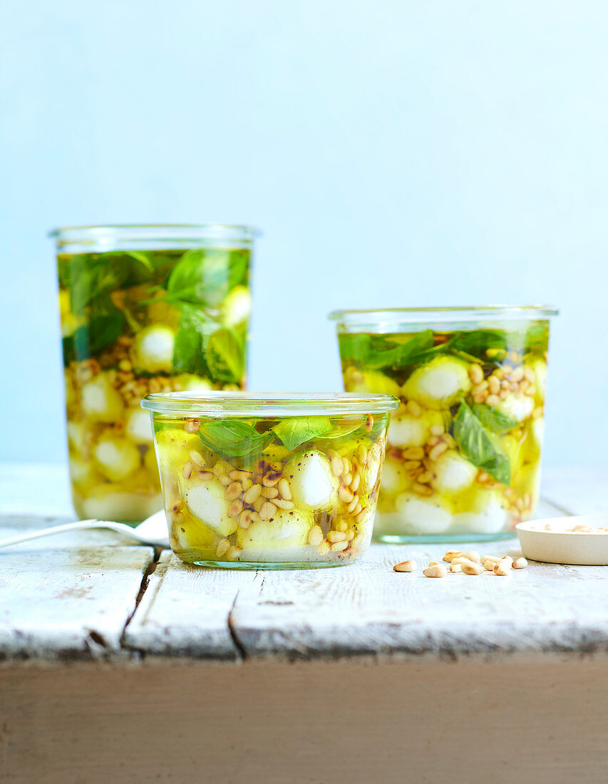 Jars of mozzarella with olive oil, pine nuts and basil