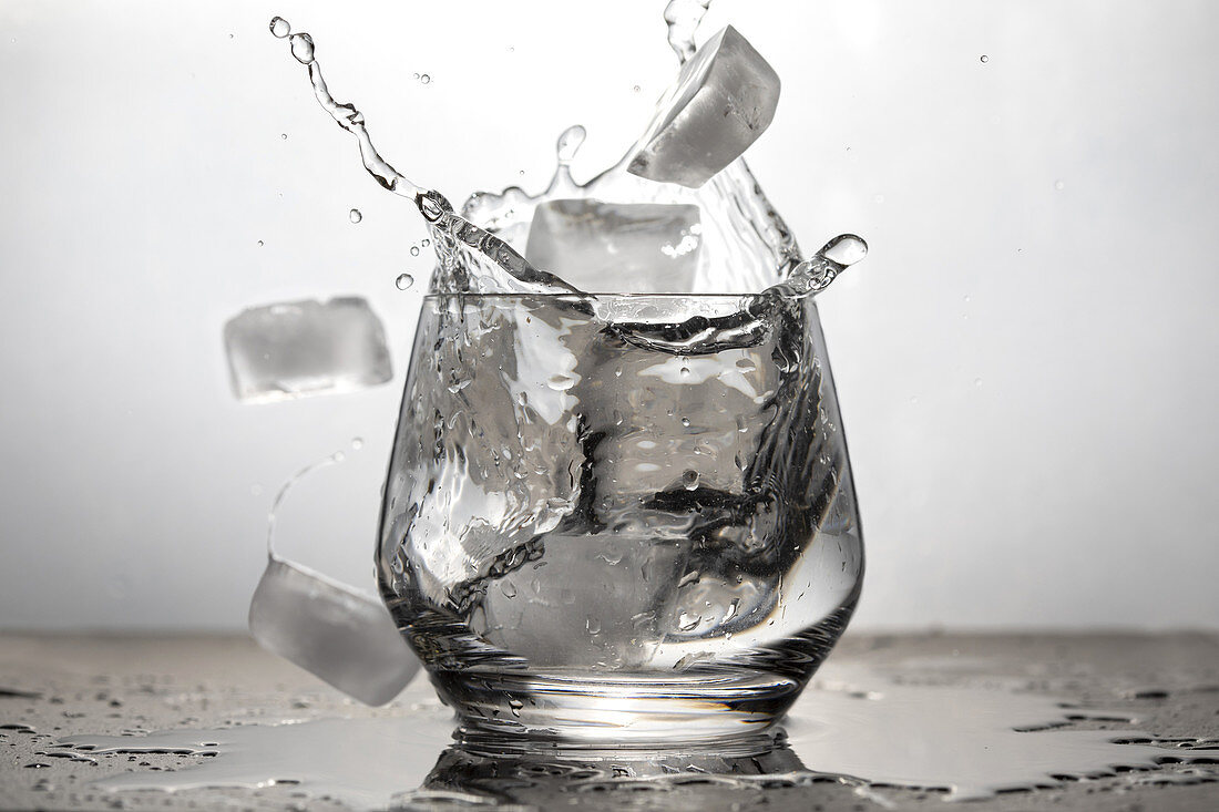Ice cubes falling into a glass of water.