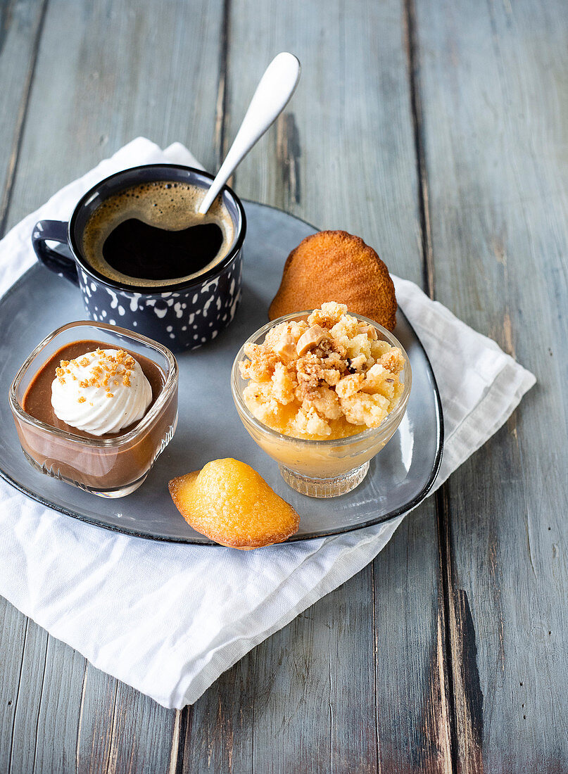 Café gourmand with small glasses of chocolate and coffee capuccino,apple crumble and Madeleine