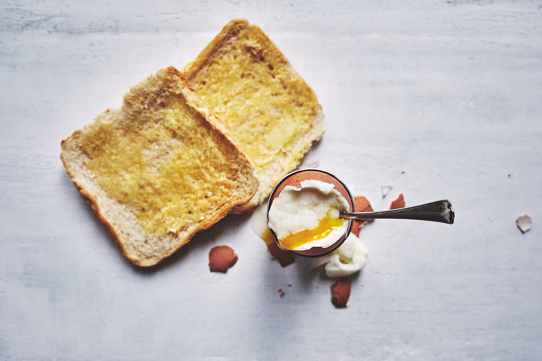 Soft-boiled egg and white bread buttered toasts