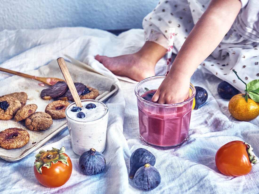 Little girl tasting fruit smooties on a table