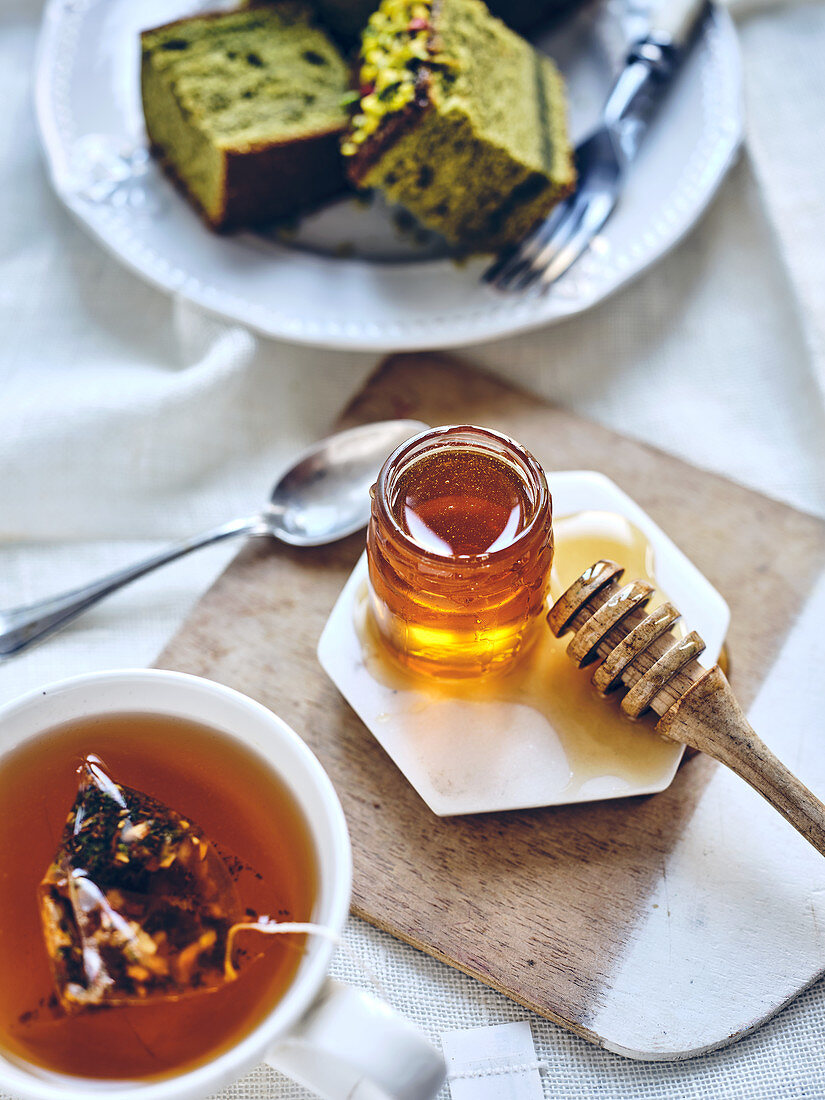 Jar of honey and green tea cake in a tea time scene