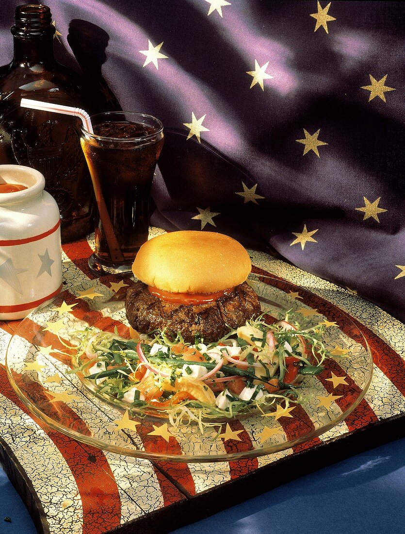 Hamburger auf Glasteller mit Salat auf Amerikaflagge