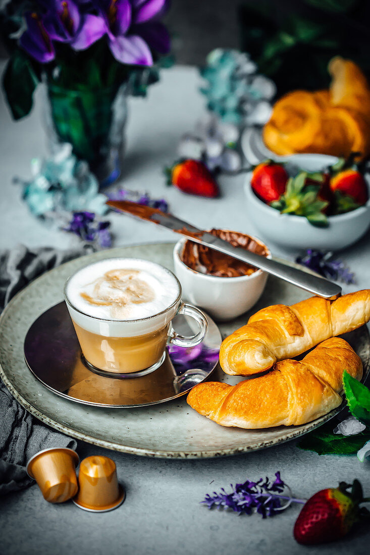 Breakfast tray with white coffee,croissant,chocolate spread and strawberries