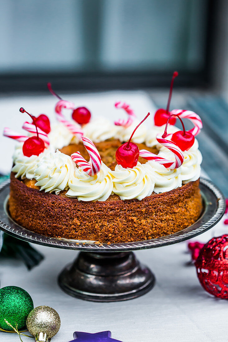 Weihnachtstorte dekoriert mit Cremetupfen, kandierten Kirschen und Zuckerstangen