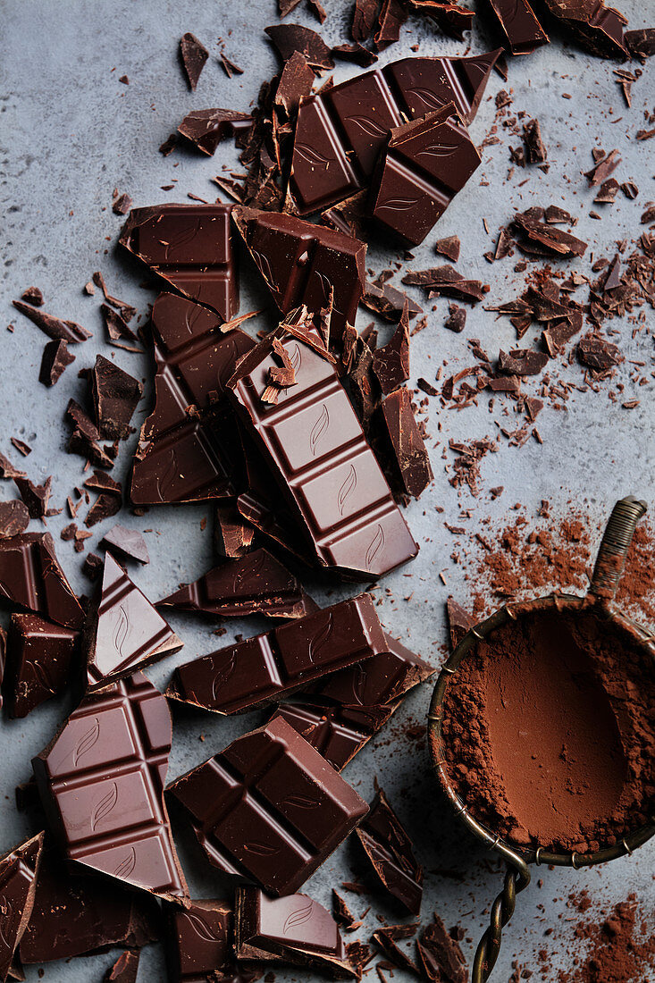 Gehackte Schokoladenstücke und Vintage-Sieb mit Kakaopulver
