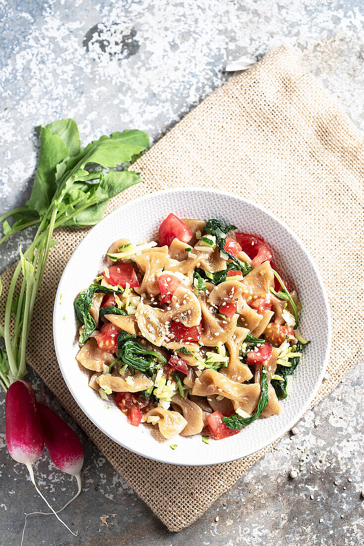 Farfalle with radish tops, tomatoes, courgettes, garlic and sesame