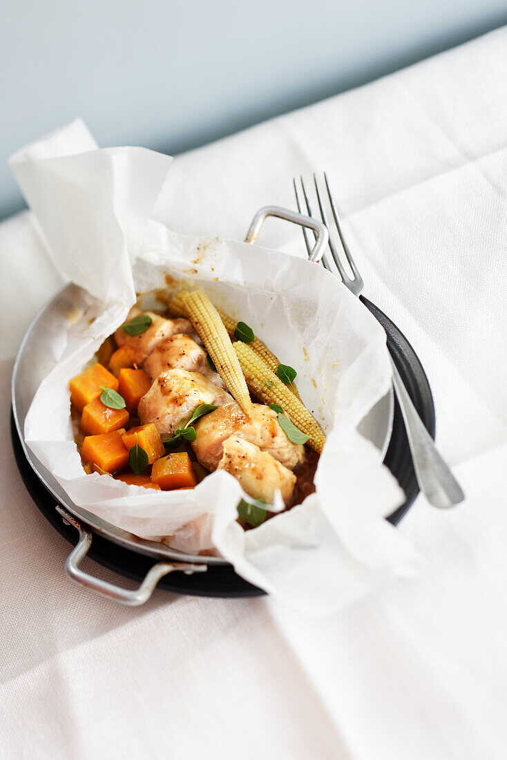 Chicken cooked in paper with honey, sweet potatoes and corn cobs