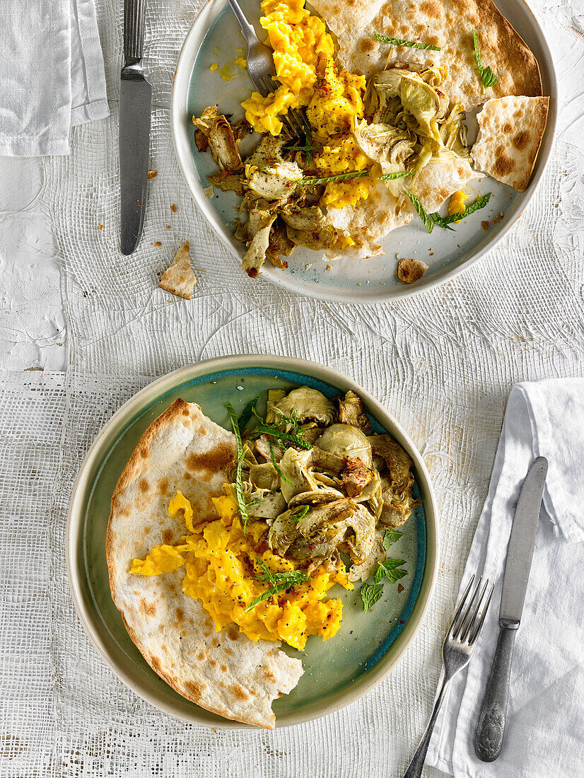 Scrambled eggs with baked artichokes, mint and pita bread