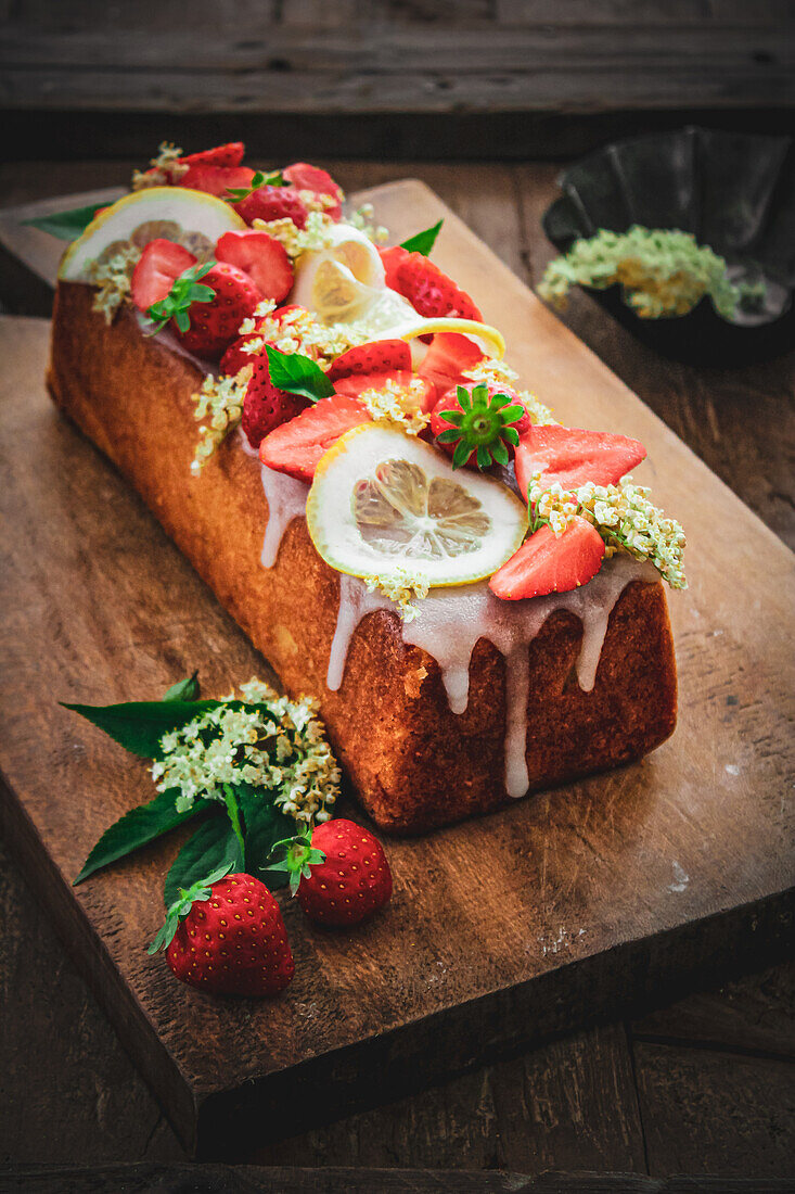 Box cake with strawberries, sugar icing and elderflowers