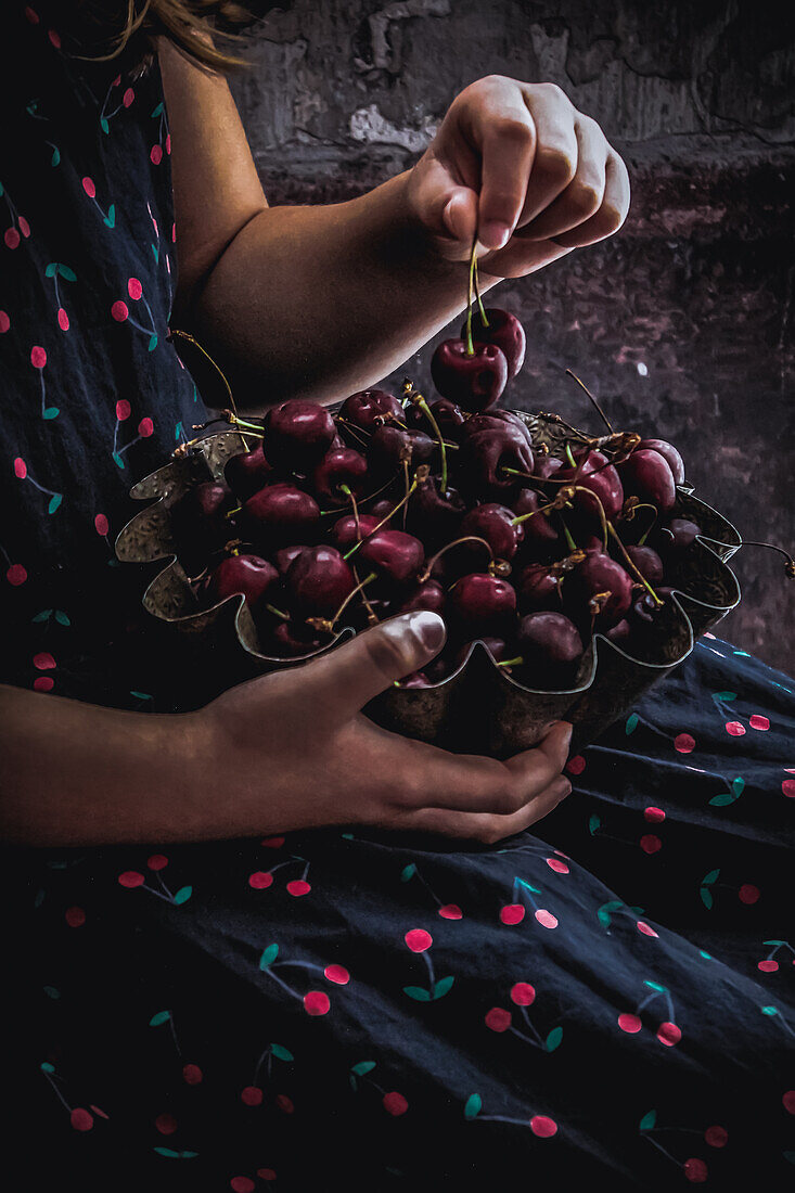 Children's hands holding a bowl of fresh cherries