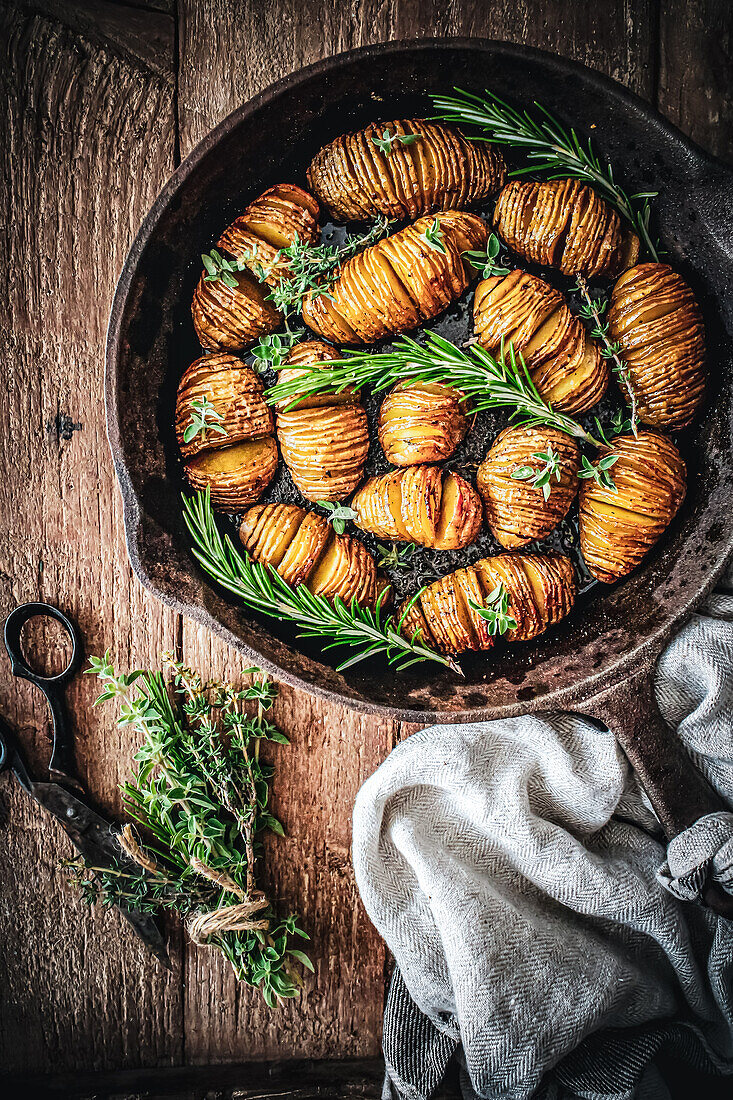 Hasselback potatoes with herbs in a pan