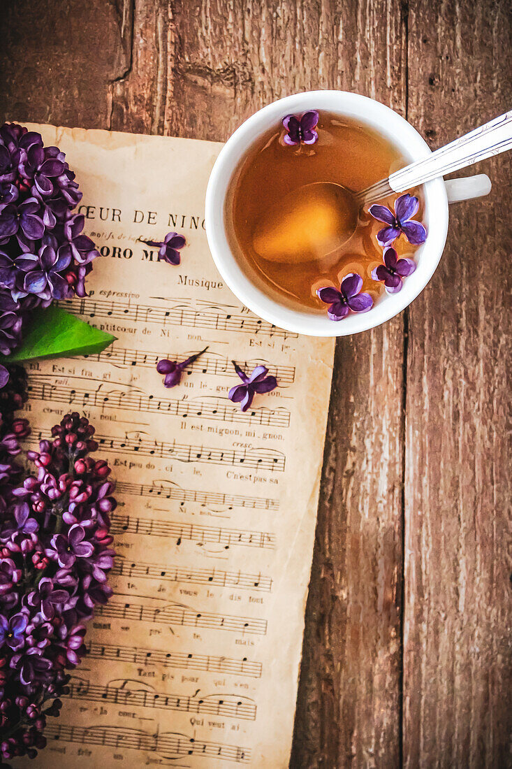 Cup of tea with lilac blossoms next to a sheet of music