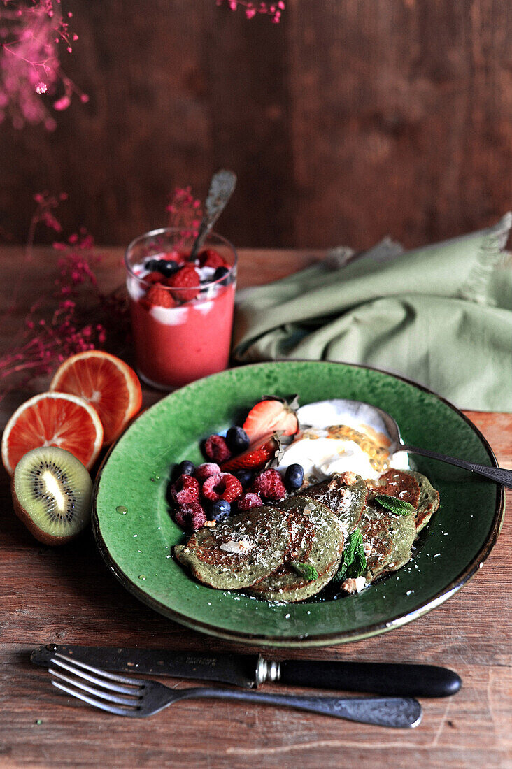 Grüne Spinat-Pancakes und roten Beeren und Sauerrahm