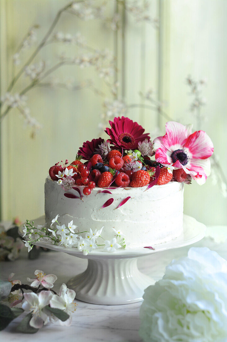 Layer cake decorated with red fruits and flowers
