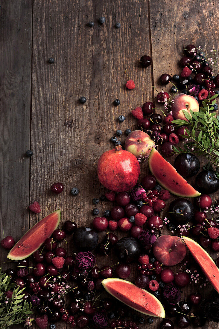 Still life with various red fruits on wooden background