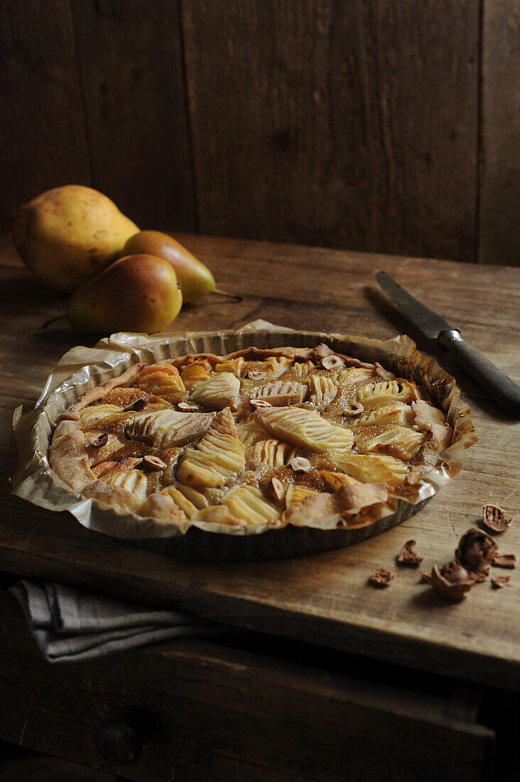 Pear tart with hazelnuts on rustic wooden table