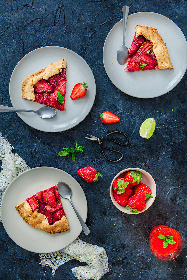 Several slices of strawberry tart with mint and lime on plates