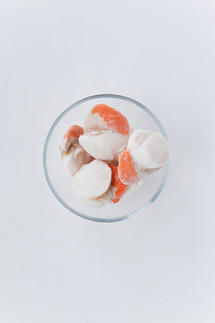 Frozen scallops with coral in a glass dish