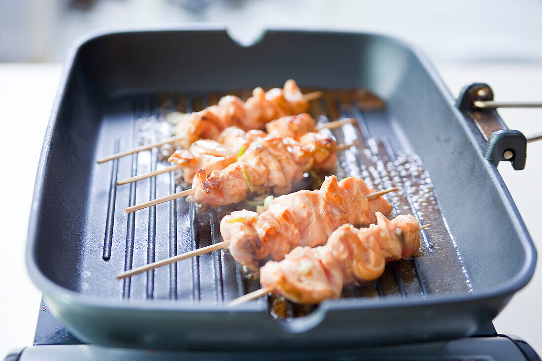 Frying salmon skewers in a grill pan