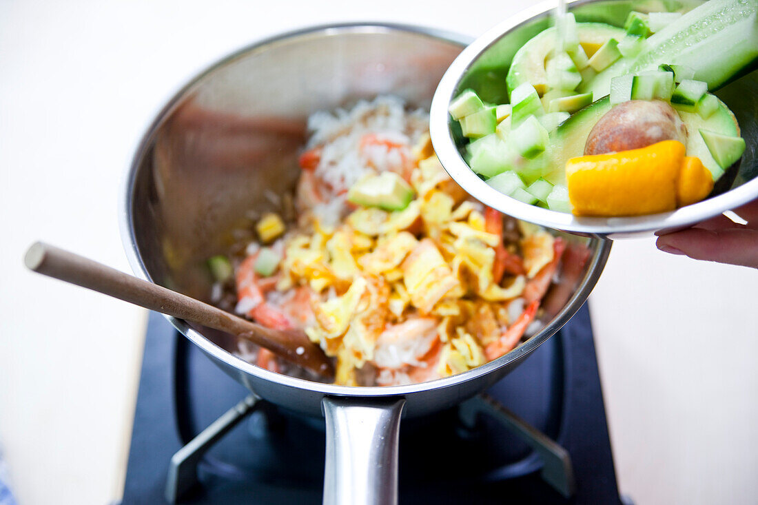 Preparing rice with prawns, avocado and omelette