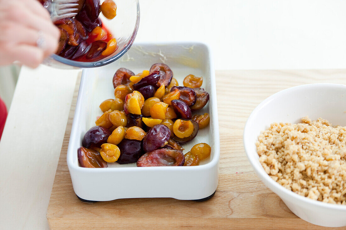 Making a plum crumble by putting the fruit in a casserole dish