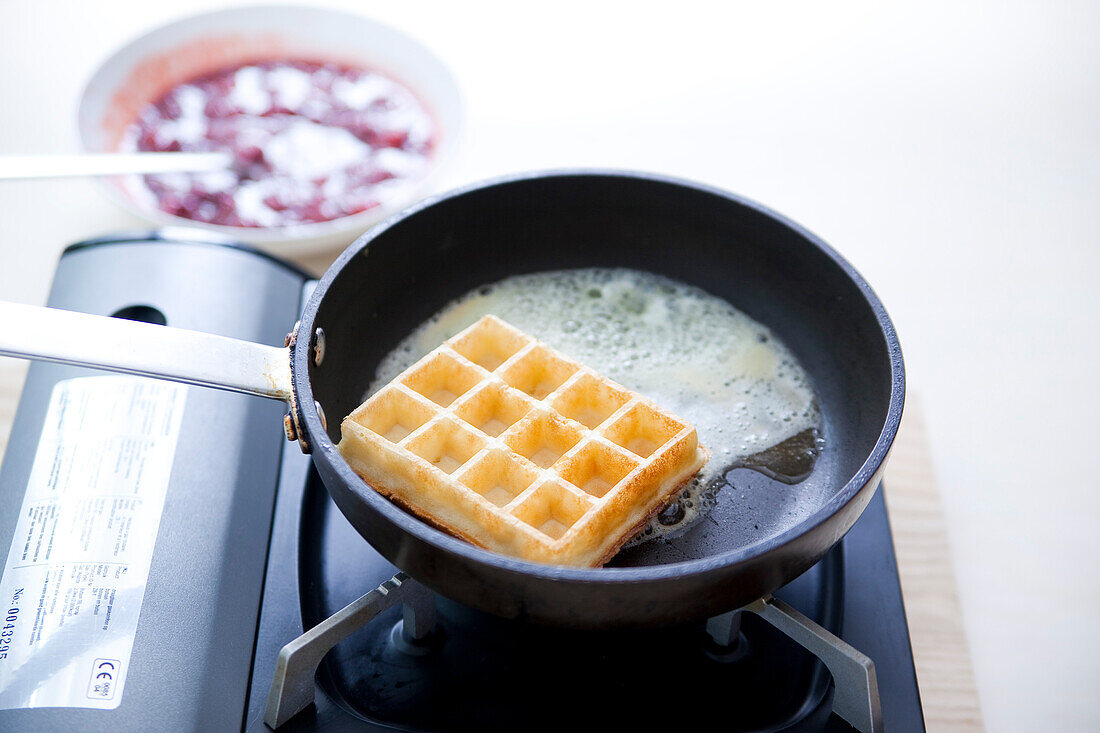 Frying waffles in a pan to serve with raspberry compote