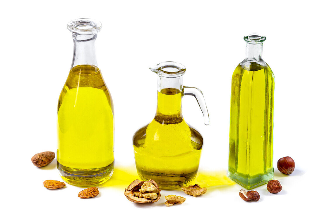 Almond oil, walnut oil and hazelnut oil in bottles against a white background