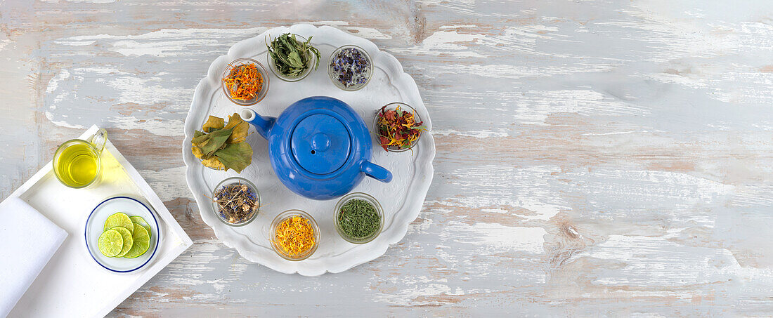 Dried medicinal plants and flowers arranged around a teapot