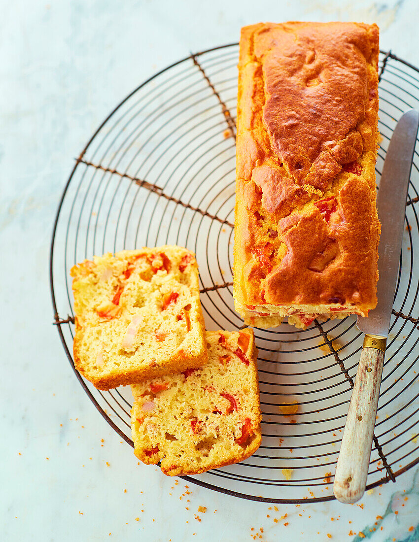 Savory spicy loaf cake with ham and tomatoes, cut on a cooling rack