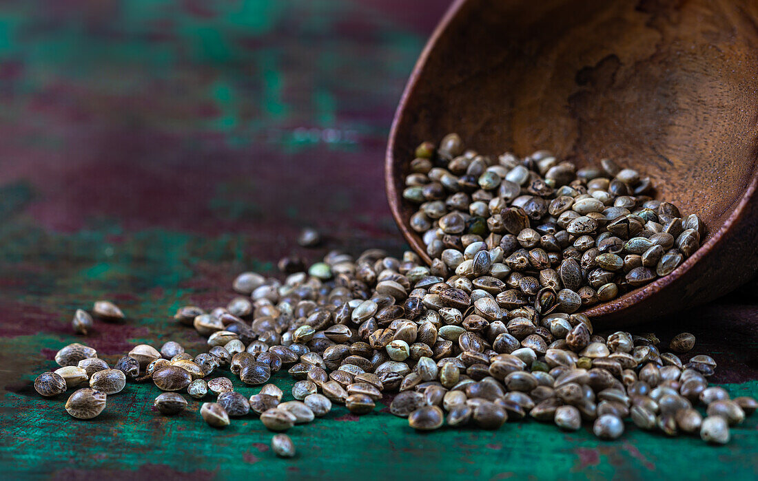 Hemp seeds on a wooden spoon and wooden background