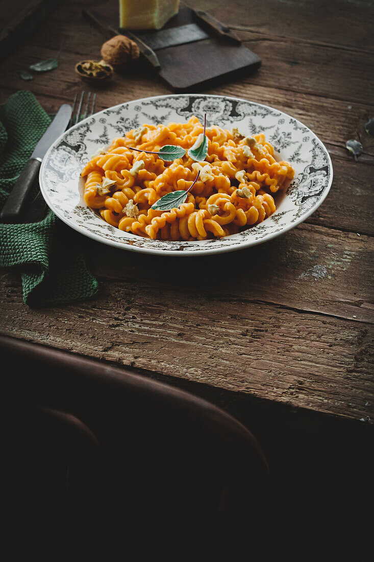 Pasta with tomatoes, cheese, and walnuts on a rustic wooden table