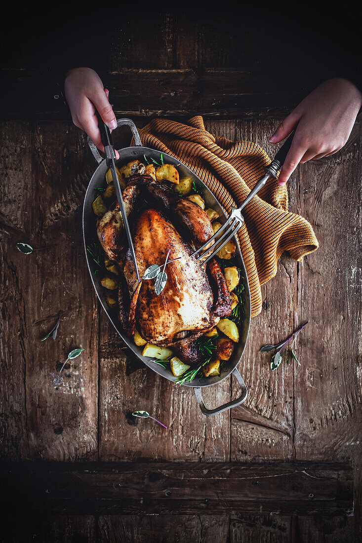 Roasted chicken with baked potatoes on a rustic wooden table