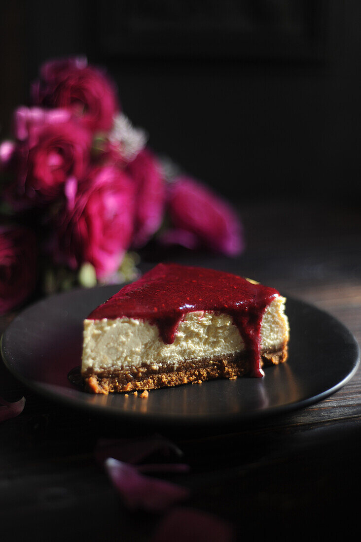 A slice of cheesecake with red fruits coulis