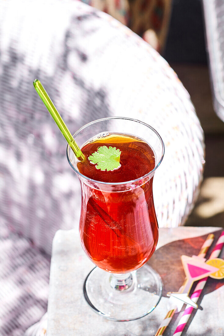 Peach ice tea with grenadine and cilantro on an outdoor table