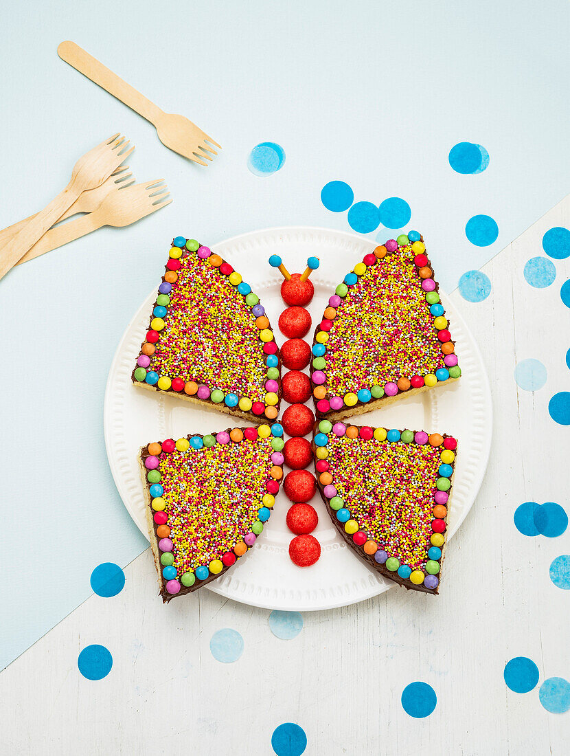 Butterfly-shaped yoghurt cake decorated with colorful sugar sprinkles and chocolate chips