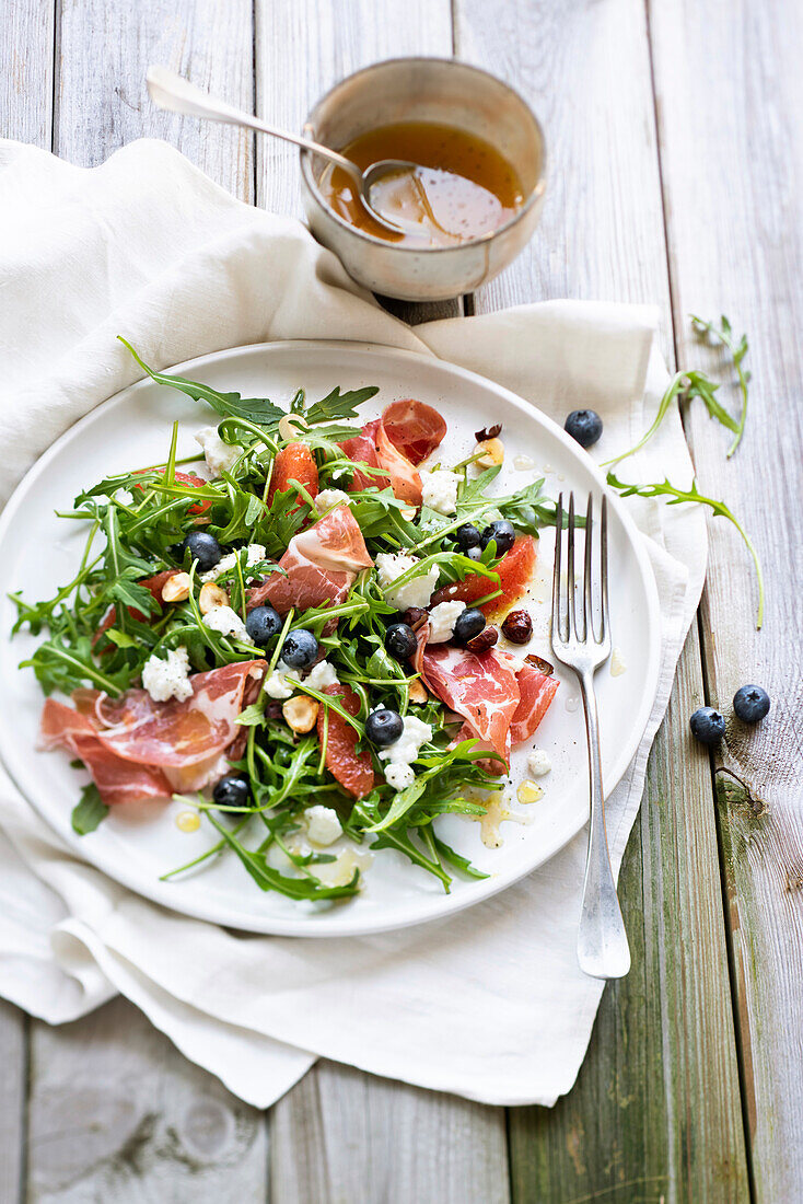 Rocket salad with coppa, blueberries, hazelnuts, pomelos and brousse