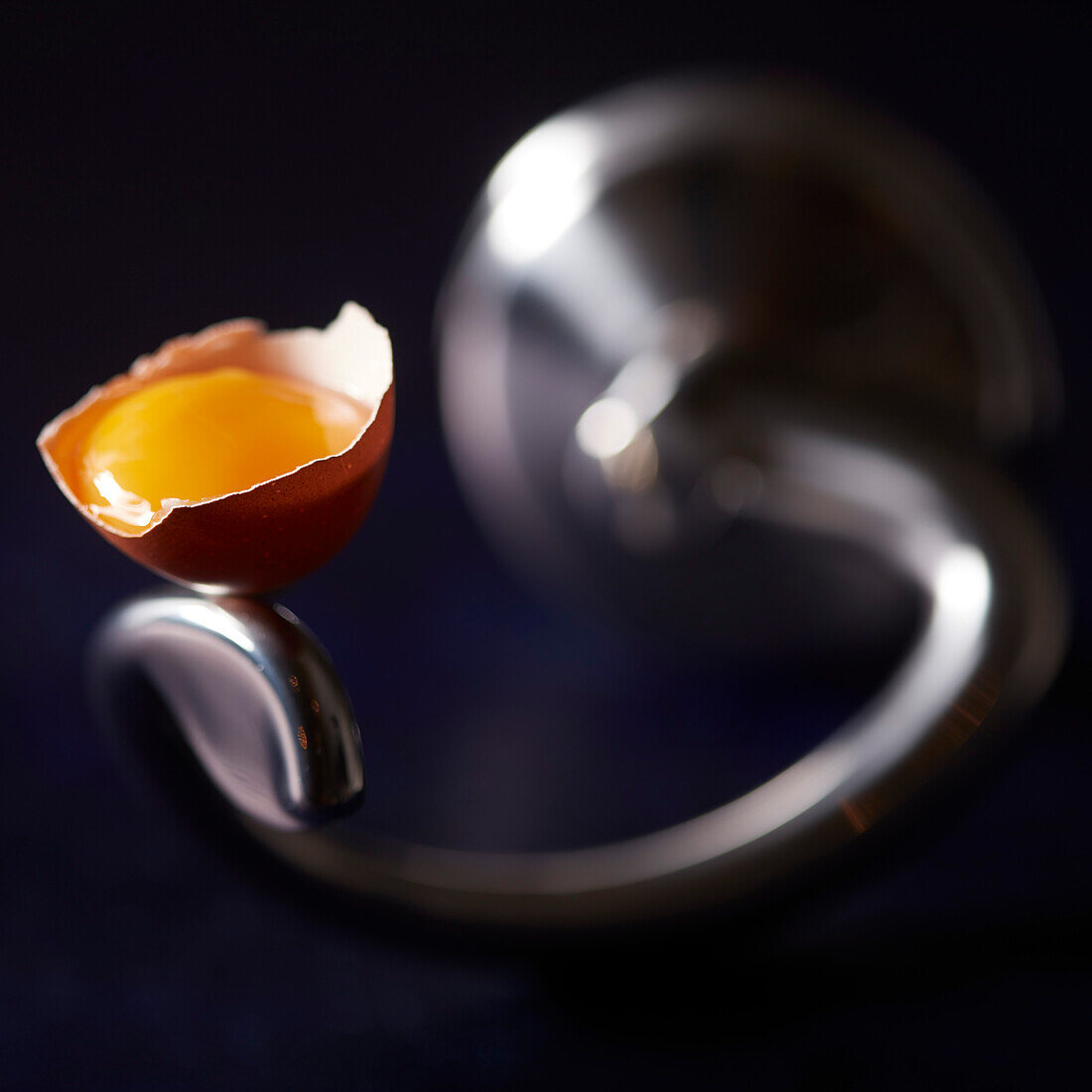 Egg yolk in half an eggshell on an electric whisk