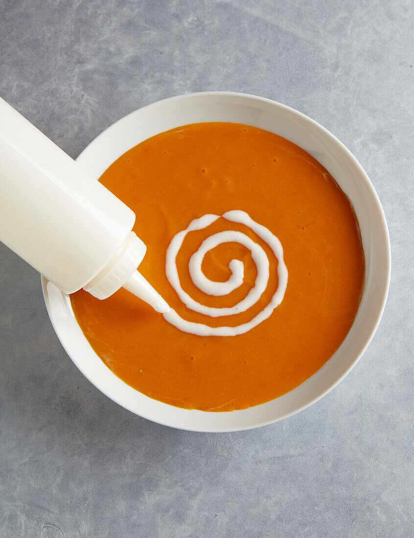 Decorating the pumpkin soup with a cream spiral