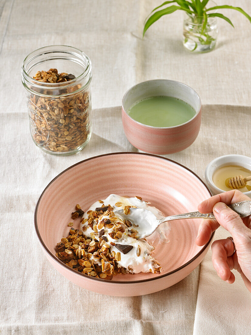 Muesli with dried fruits and chocolate mixed with curd cheese served with a cup of green tea