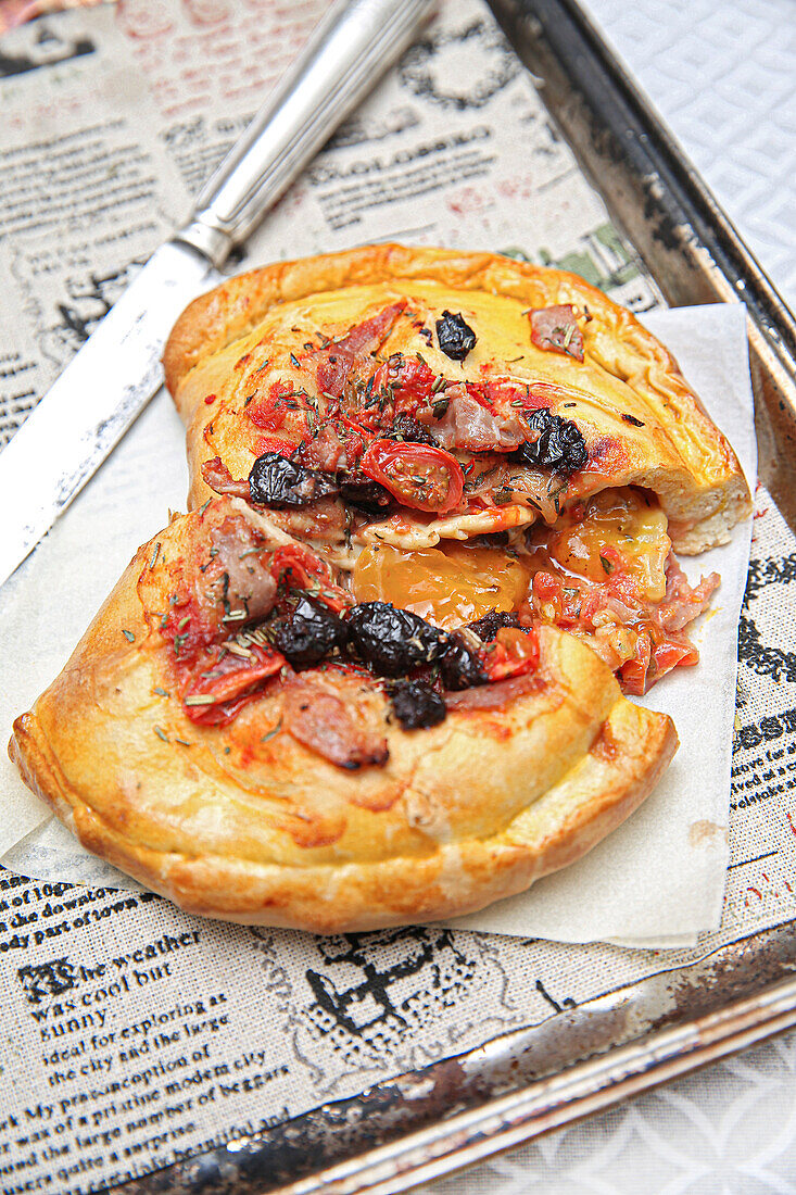 Calzone with cherry tomatoes, Parma ham, black olives, chilli and egg